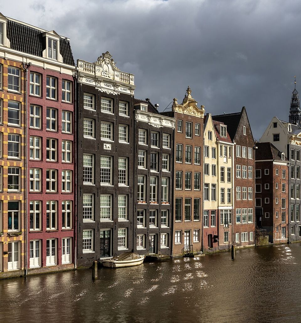 Colorful canal houses at golden hour in Damrak avenue Amsterdam the Netherlands